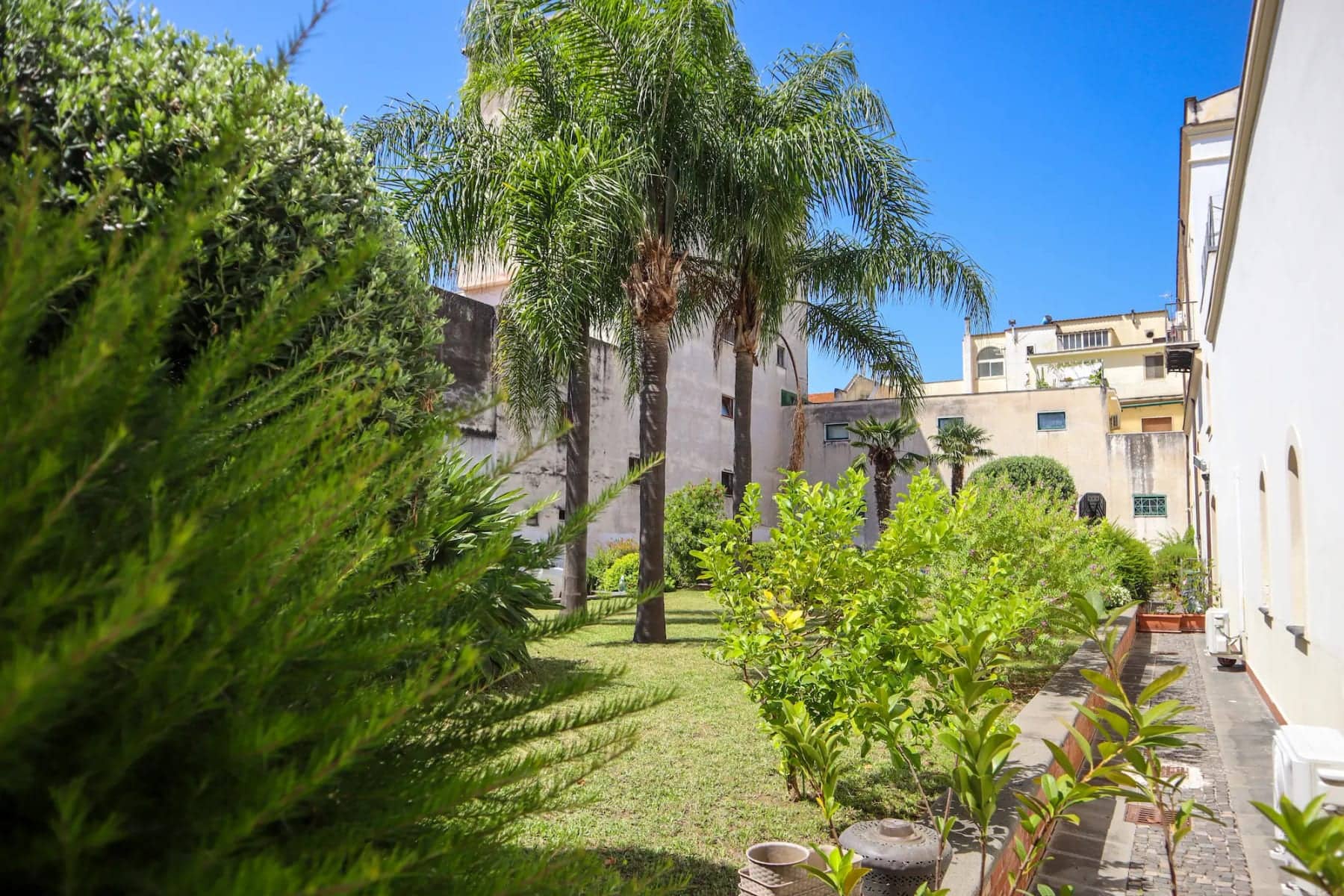 Il giardino interno del Pompei Hostel Deluxe con palme e piante mediterranee